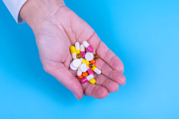 istock Different pills in a female hand on a blue background. Medicines. Treatment. 1203528715