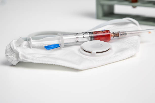 istock disposable mask and syringe with blood samples on a white background 1203530451