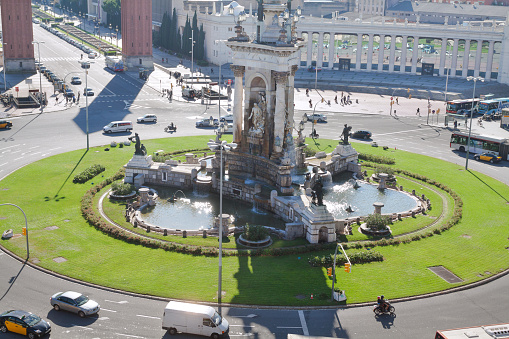 Aerial view to roundabout Placa de Espanya with huge monumental fountain in center of square. Traffic is ruling in streets. Square is one main squares with a lot old architecture around in Barcelona.