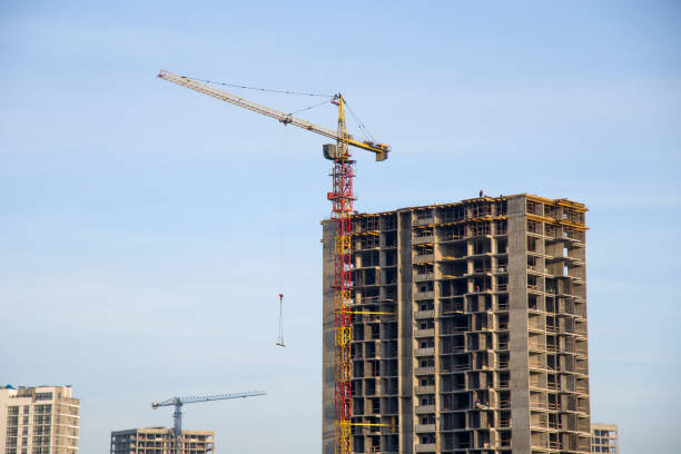 istock Tower crane lifts the block for building under construction at background blue sky 1203534813