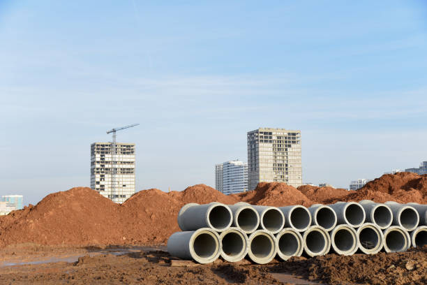 Concrete drainage pipes at the construction site. Laying of underground storm sewer pipes. Installation of water main, sanitary sewer. Installation of concrete sewer wells in the ground