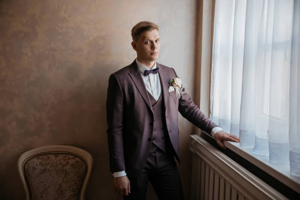 istock close up. brooding groom standing near the window. 1203536599