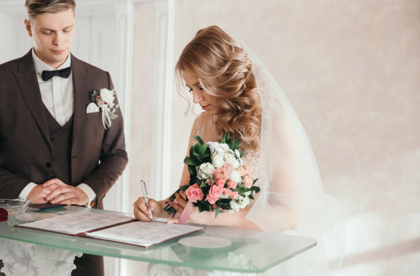 istock bride and groom signing the marriage contract. 1203537409