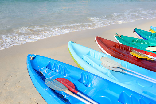Kayaks near the water on sand beach. Colorful boats in front of sea coast. Vacation and travel sport activity. Free copy space.