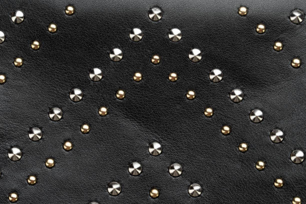 Black leather abstract rock background with rows of metal rivets.