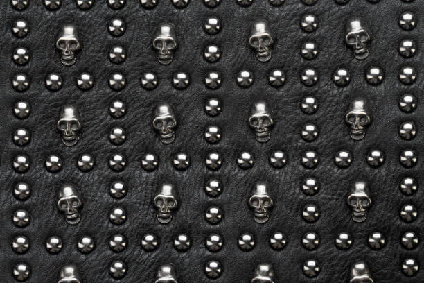 black leather abstract rock background with metal rivets black leather abstract rock background with metal rivets in the form of skulls. metal stud stock pictures, royalty-free photos & images
