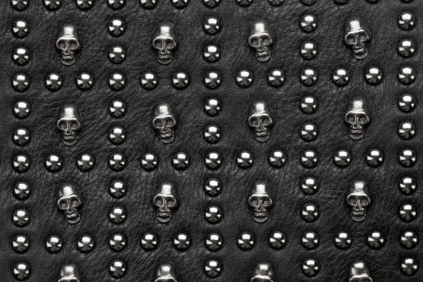 black leather abstract rock background with metal rivets in the form of skulls.