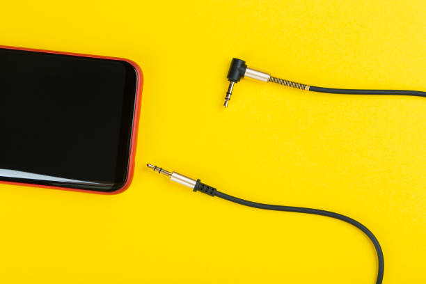 istock Close-up Jack plug and a cable with phone on a yellow background 1203539756