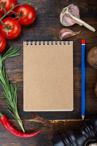 istock vegetables and a paper notebook on a spiral, on a brown wooden background. 1203539820