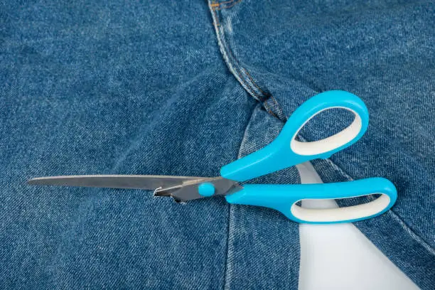 Make a hole in blue jeans with scissors