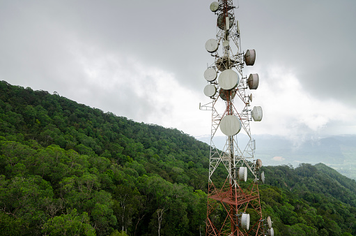 Radio, television and communication antenna tower on the hilltop over cloudy sky background