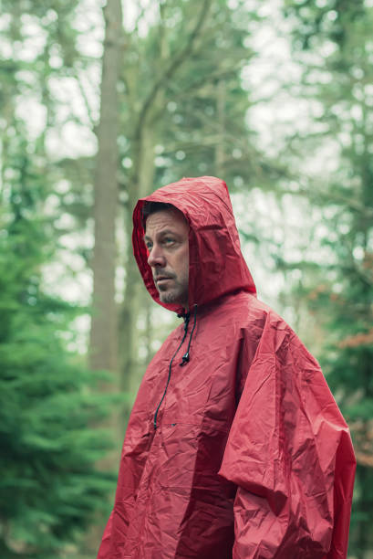 istock Man in red hooded raincoat in forest. 1203545650