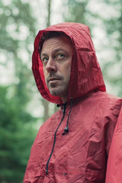 istock Man in red hooded raincoat in forest. 1203545661