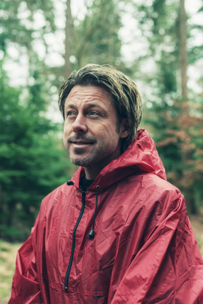 istock Smiling man in red raincoat in woods. 1203545673