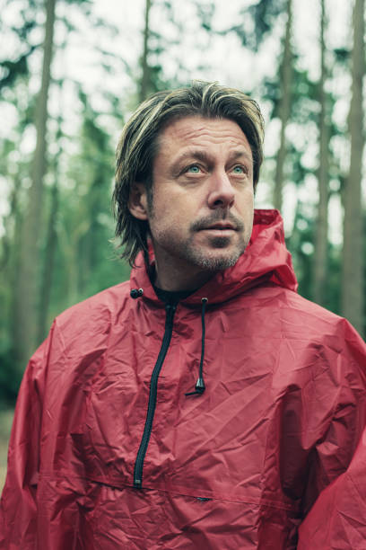 istock Man in red raincoat in woodland. Looking up. 1203545694