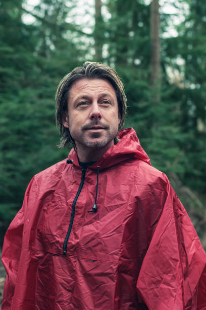 istock Smiling middle aged man in red raincoat in woods. 1203546773