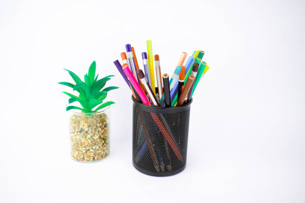 istock A tree and a jar full of different colored pencil crayons placed before a white background 1203554818
