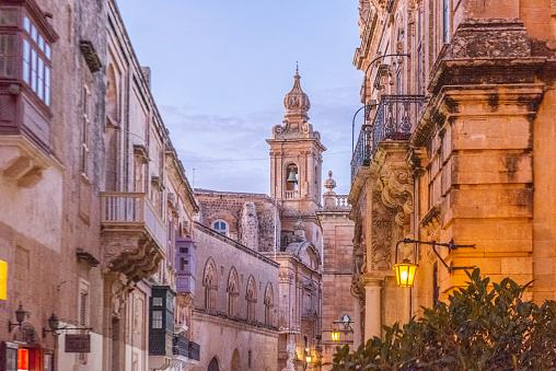 View of the bell tower of the baroque Metropolitan Cathedral of Saint Paul during the sunset at Mdina city in the Republic of Malta.