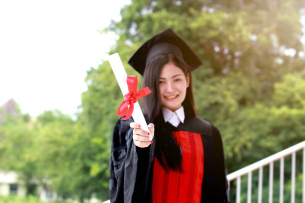 istock Happy graduated student wearing a black hat, holding certificate on hand finish studies at university, graduation day concept 1203557776