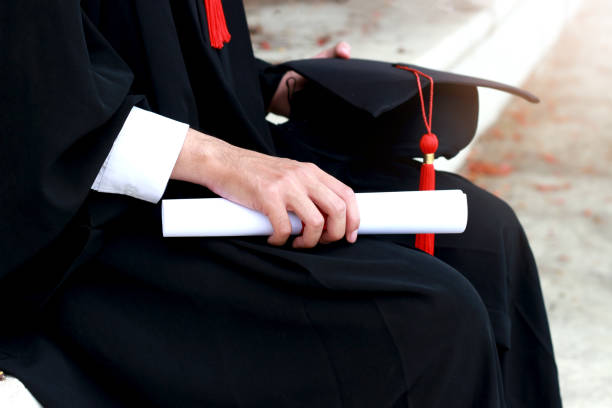 istock Graduation hat and certificate in hand of graduated student on graduation day 1203557777