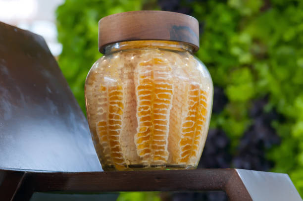 Organic honey in honeycombs inside in glass jar.