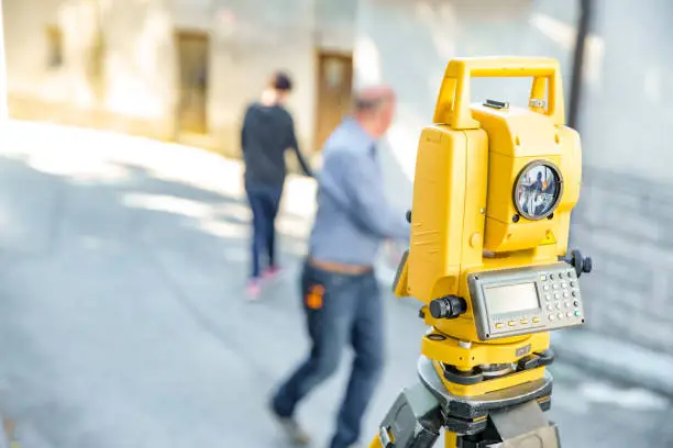 Photo of Theodolite With Surveyors in Background - Stock Photo