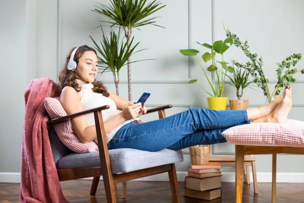 自宅で音楽を聴く若い女性 - armchair comfortable relaxation headphones ストックフォトと画像