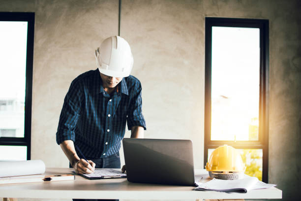 istock engineer working on blue print and search on laptop in construction site 1203560645