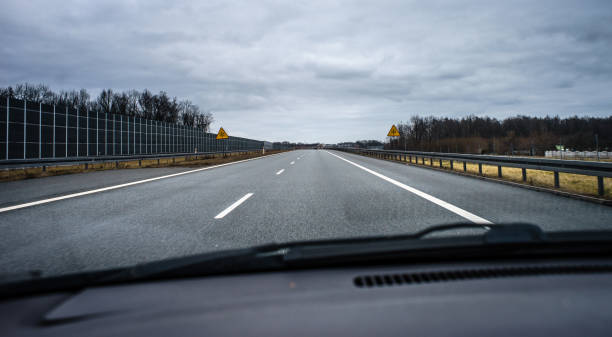 istock A two-lane highway seen from a moving car through the windshield. 1203561707