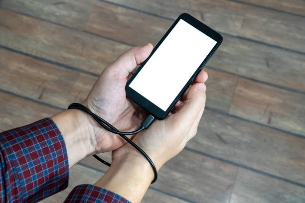 istock Social media obsession concept. Phone charging cable tangled around the hand 1203566215