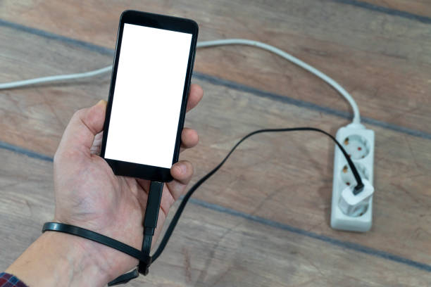 istock Electricity dependence concept. Man holding phone connected to a power strip 1203566259