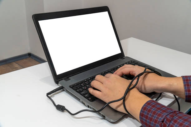 istock Modern problems concept. Man typing on laptop with hands tangled in the cable 1203566751