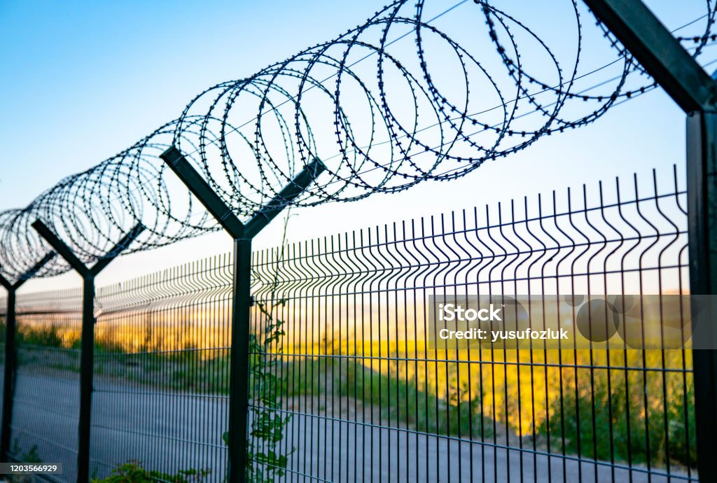 Steel Grating Fence Of Soccer Fieldmetal Fence Wire With Bokeh In The  Background Coiled Razor Wire With Its Sharp Steel Barbs On Top Of A Wire  Mesh Perimeter Fence Ensuring Safety And