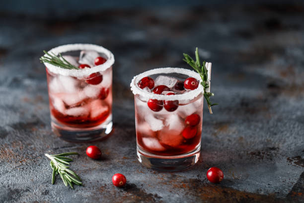 cocktail di mirtilli rossi con ghiaccio. bevanda di mirtillo natalizio in bicchieri decorati con zucchero e rosmarino - cranberry juice foto e immagini stock