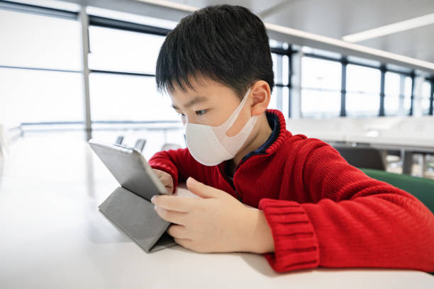 chico comprobando la información del coronavirus con máscara en el aeropuerto - china shanghai business people fotografías e imágenes de stock