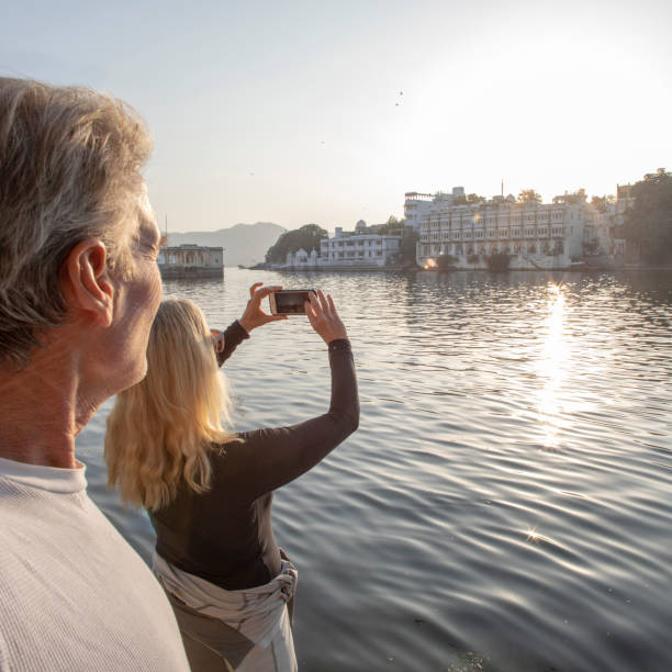 Mature couple explores a ghat at sunrise, she takes a photo across the lake Lake Pichola, Udaipur lake palace stock pictures, royalty-free photos & images