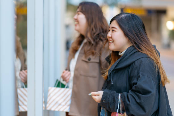 istock Two female friends doing window shopping 1203570608