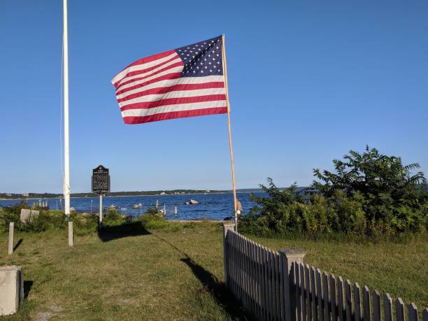 istock New England waterside scene and American flag 1203573478