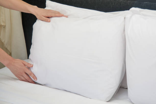 istock Hotel room service. Hands set up white pillow on the bed. 1203575750