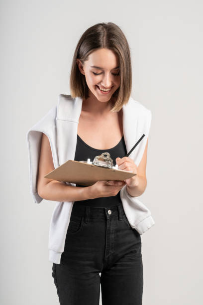istock Smiling young casual woman writing in clipboard 1203577078