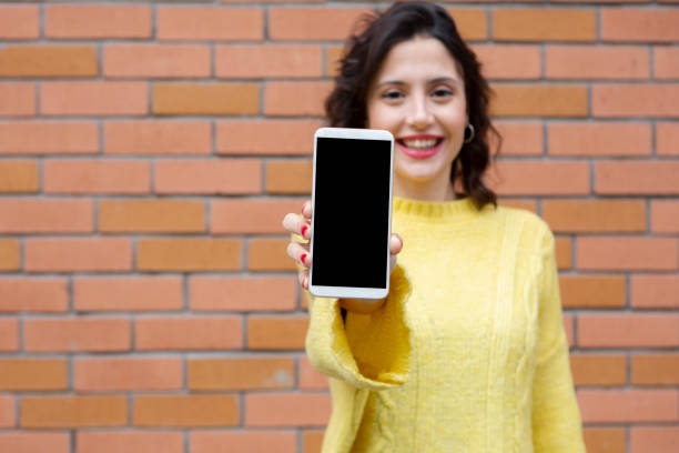istock Young woman showing smart phone 1203577255