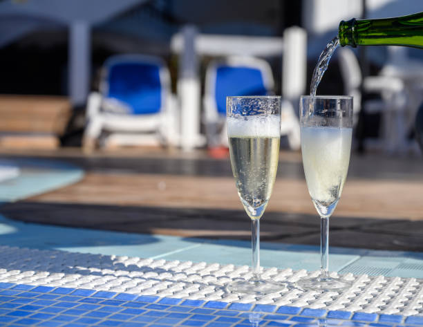 istock Pool party with two glasses with  bubbles white champagne or cava wine, romantic event or all inclusive holidays 1203579362