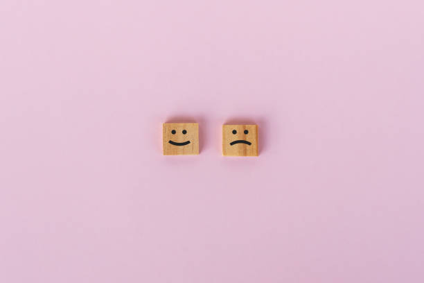 Sad and smiling symbol on wooden block Sad and smiling symbol on wooden block, pink background. malaysian-happy-faces stock pictures, royalty-free photos & images