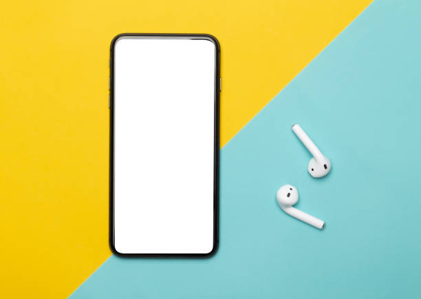 Black smartphone with blank screen and wireless earphones isolated on yellow and blue background. Clipping path Black smartphone with blank screen and wireless earphones isolated on yellow and blue background. Clipping path. podcast mobile stock pictures, royalty-free photos & images