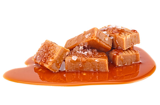 Delicious candies with caramel sauce and salt isolated on a white background