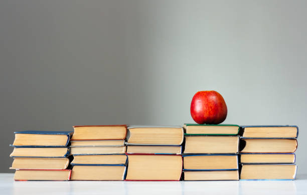istock stack of hardback books on white table with red apple. Books stacking. Back to school concept. Copy Space. Education learning background 1203580820