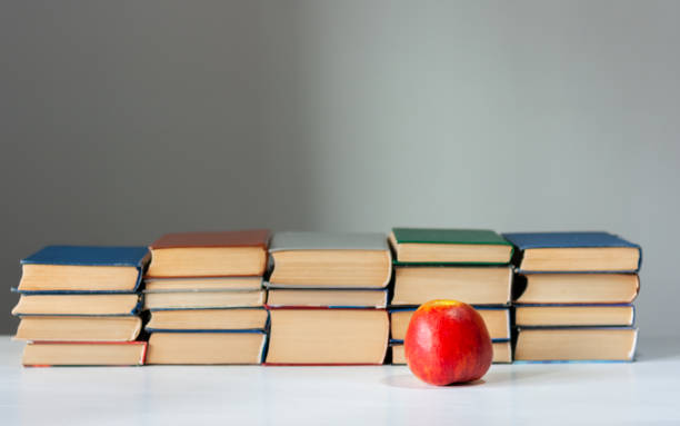 istock stack of hardback books on white table with red apple. Books stacking. Back to school concept. Copy Space. Education learning background 1203580874
