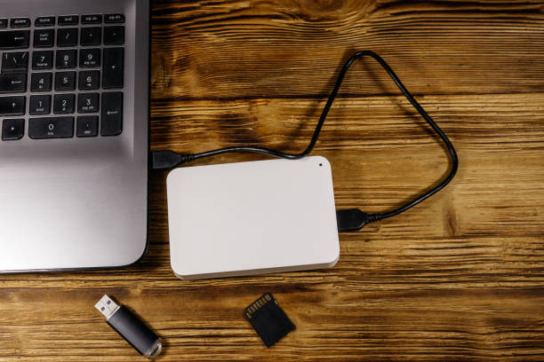 istock External HDD connected to laptop computer, SD memory card and USB flash drive on a wooden desk. Top view. Concept of data storage 1203584836