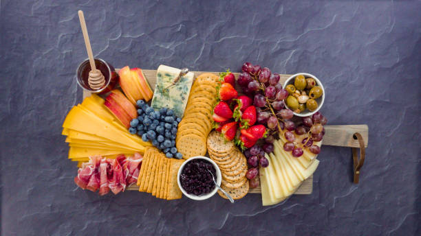 istock Arranging gourmet cheese, crakers, and fruits 1203585356