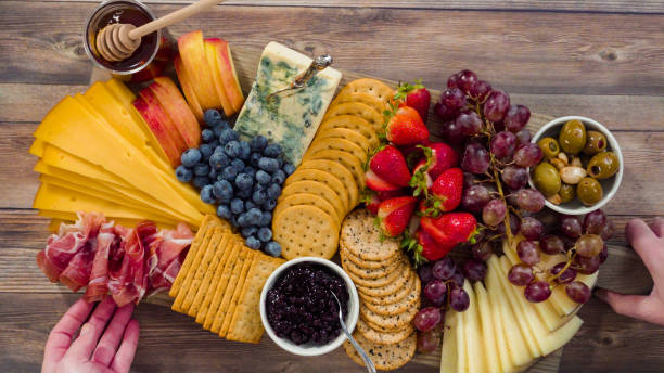 istock Arranging gourmet cheese, crakers, and fruits 1203585961